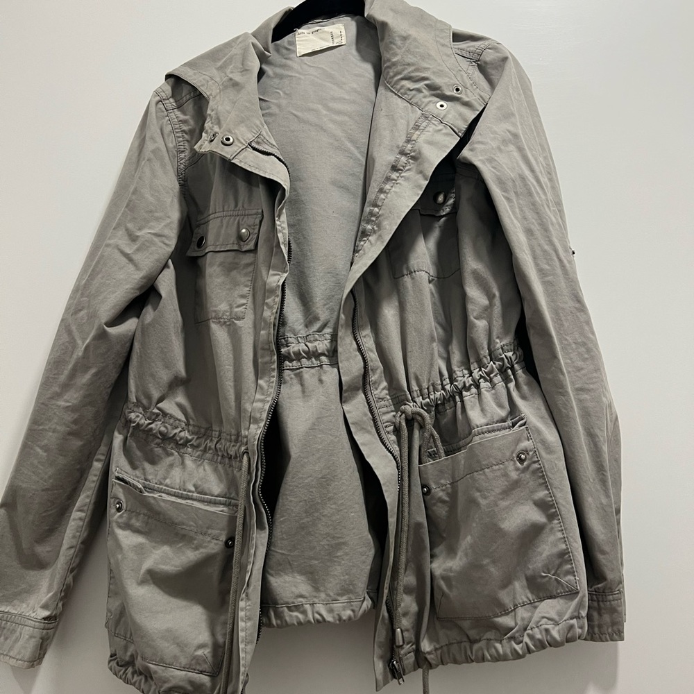 Gray utility/rain jacket with adjustable string ties around waist/hips with hood